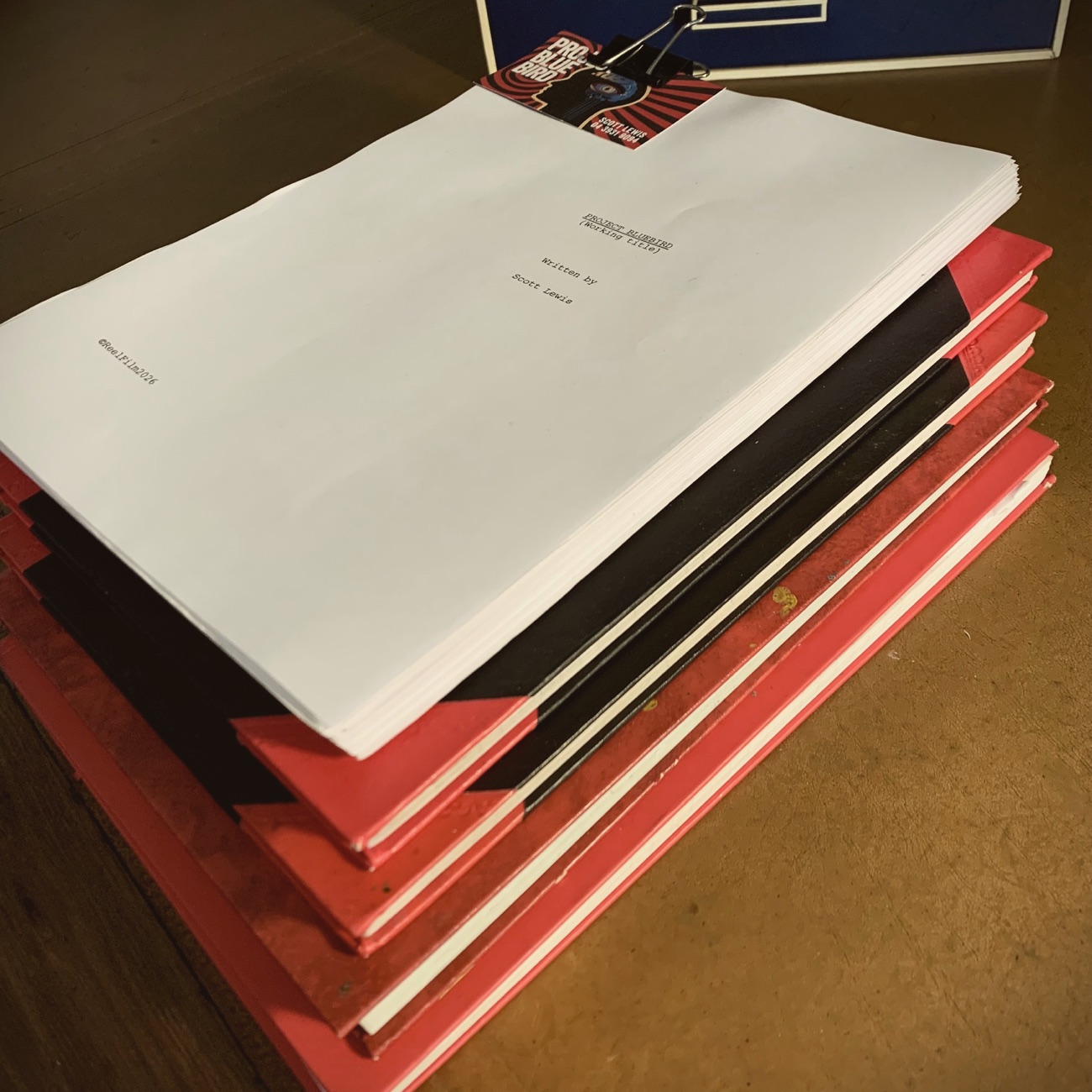 The Project Bluebird working-title script on a stack of red notebooks